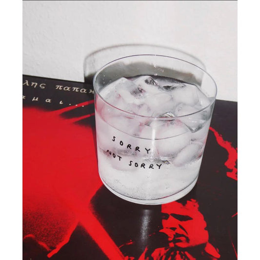Verre transparent avec texte manuscrit noir “Sorry Not Sorry”
