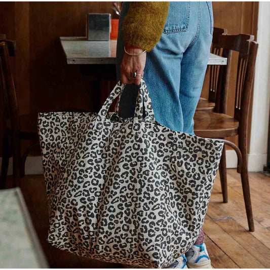 sac cabas Graou Grège Rose in April porté sur la plage, imprimé léopard noir sur fond écru