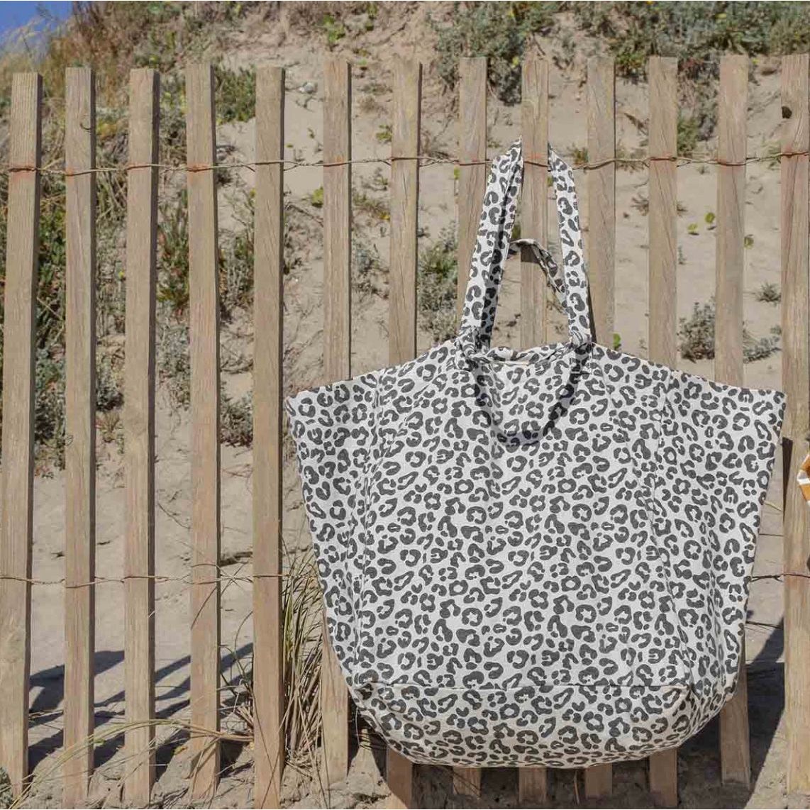 sac cabas Graou Grège Rose in April porté sur la plage, imprimé léopard noir sur fond écru