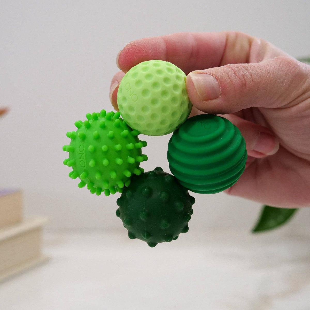 Pack ONO Émeraude de quatre balles magnétiques anti-stress en silicone vert avec textures variées dans un étui zippé noir
