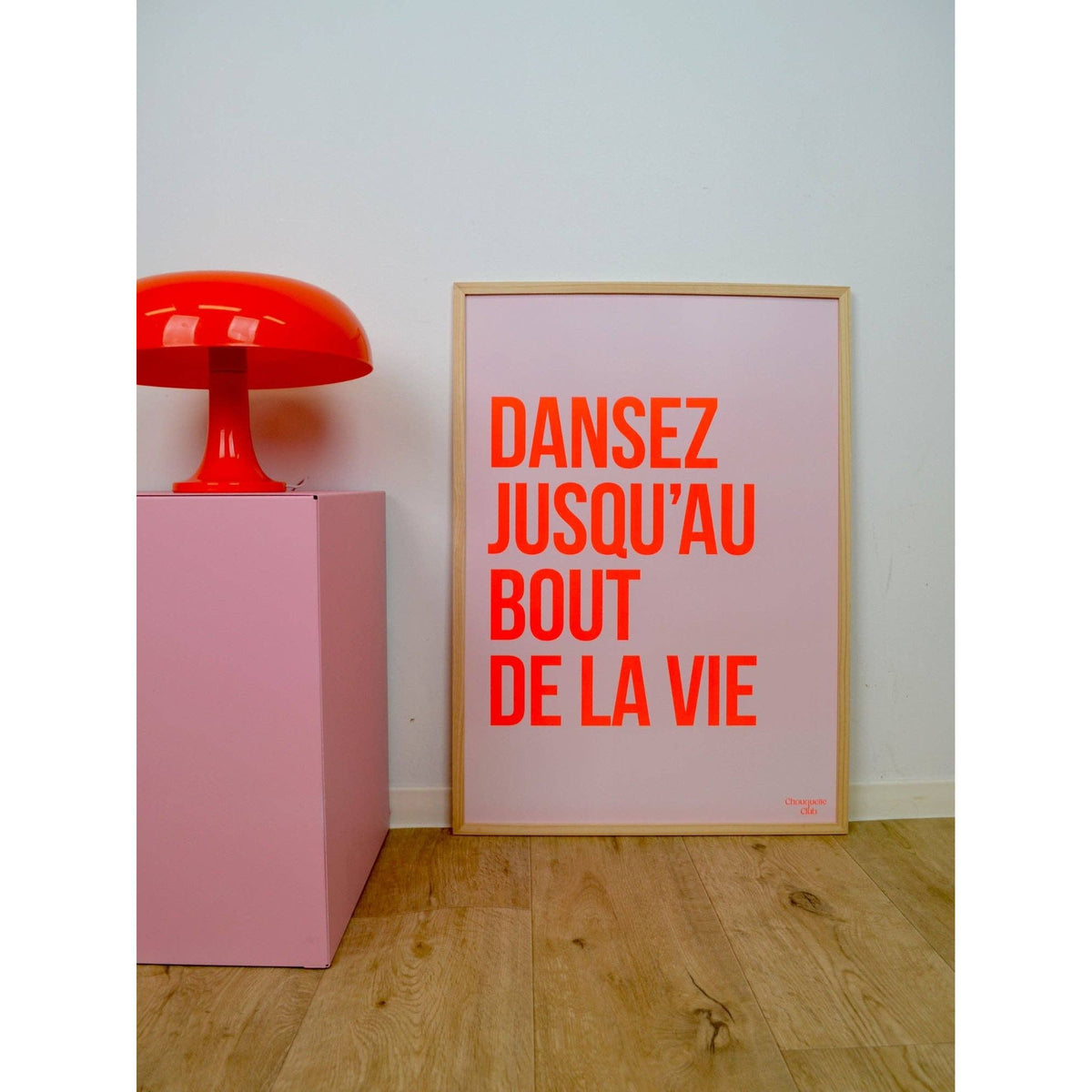 Affiche Dansez jusqu’au bout de la vie Chouquette Club 50 x 70 cm avec texte rouge sur fond rose pâle dans un intérieur contemporain