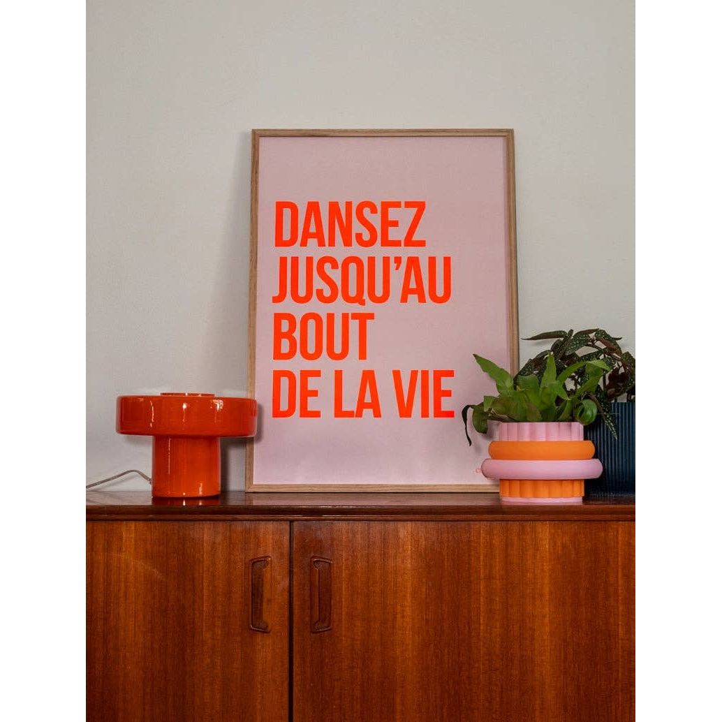 Affiche Dansez jusqu’au bout de la vie Chouquette Club 50 x 70 cm avec texte rouge sur fond rose pâle dans un intérieur contemporain