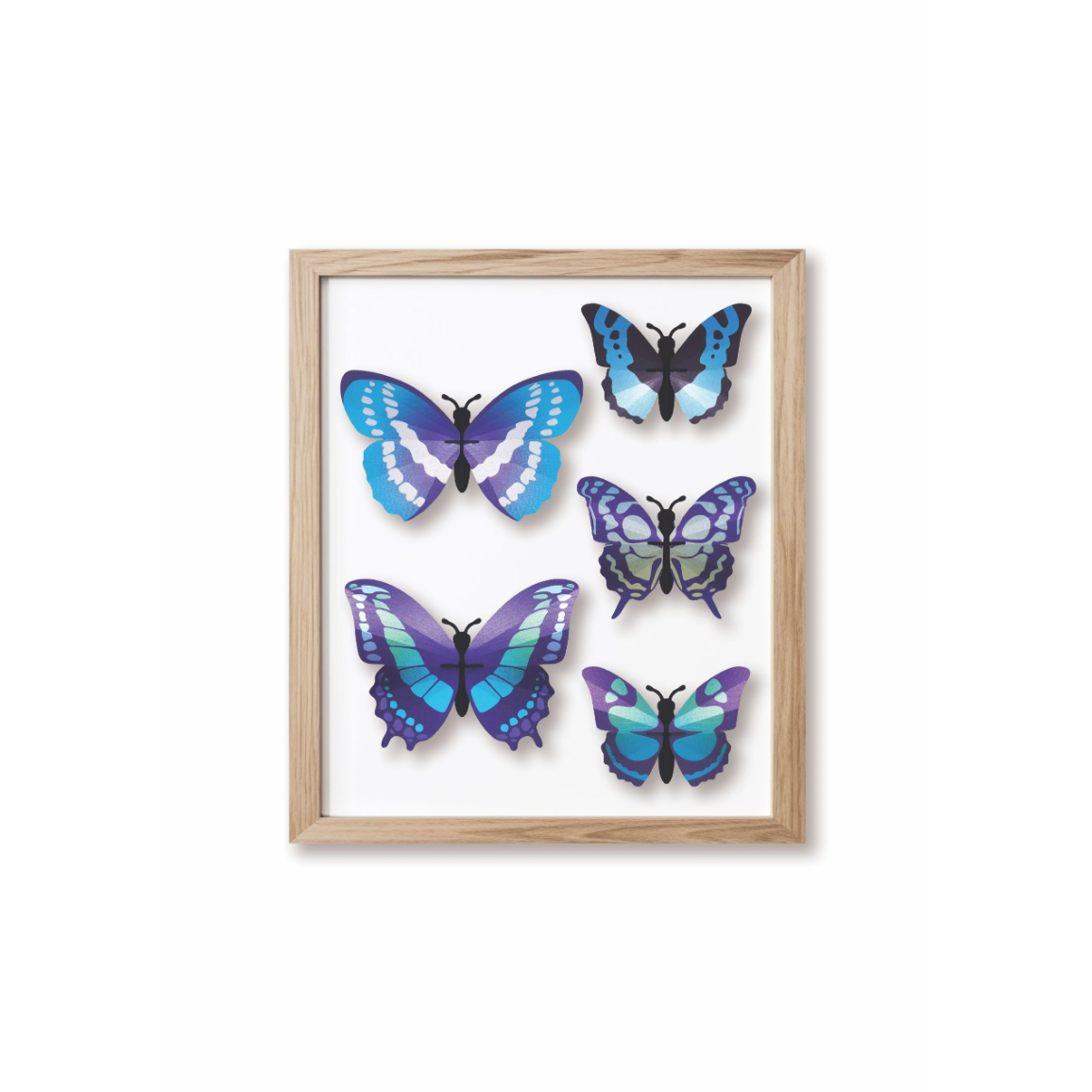 Ensemble de quatre papillons 3D Assembli en papier bleu, turquoise et violet présenté dans un cadre en bois