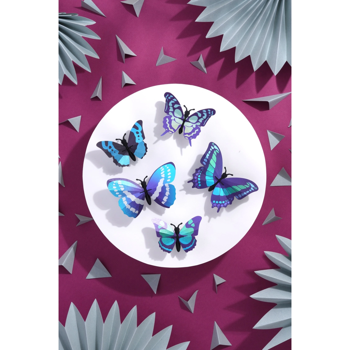 Ensemble de quatre papillons 3D Assembli en papier bleu, turquoise et violet présenté dans un cadre en bois